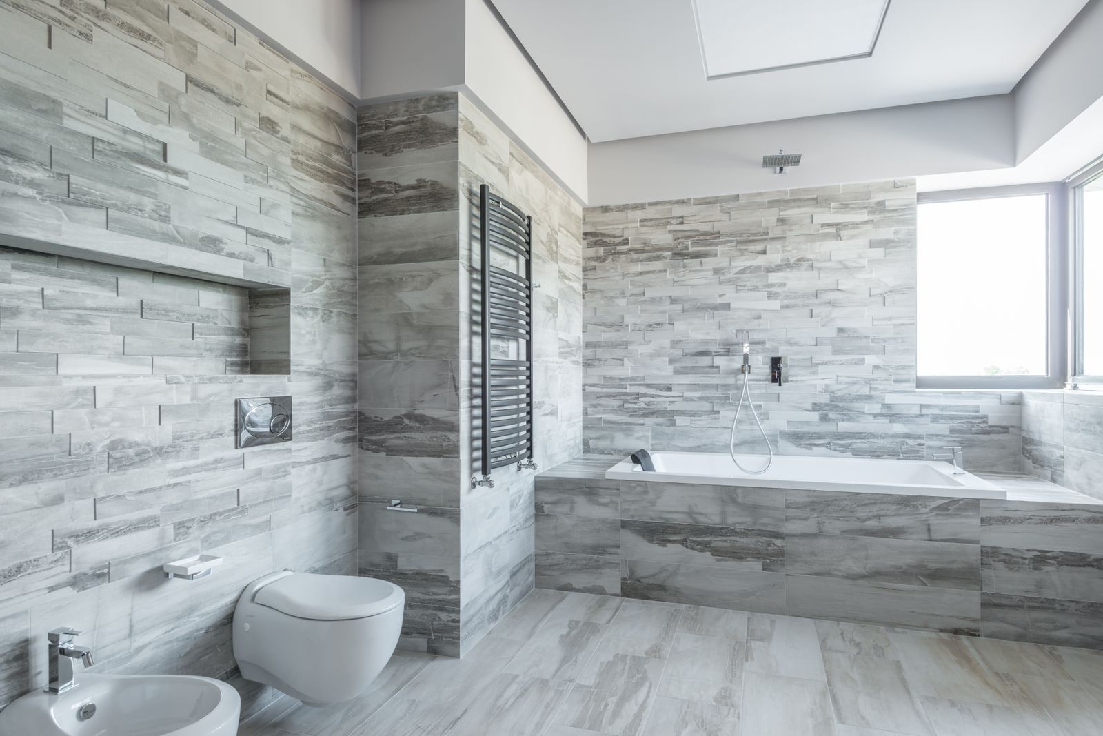 Spacious bathroom with a built-in tub and stone tile across the whole wall