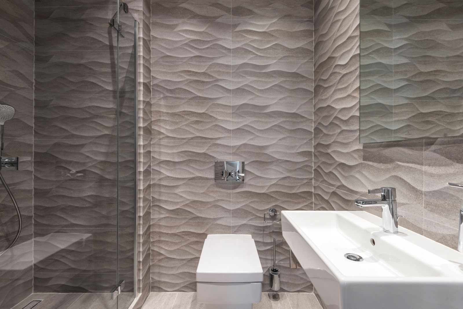 Finished bathroom with large-format tile and a wall-mounted sink
