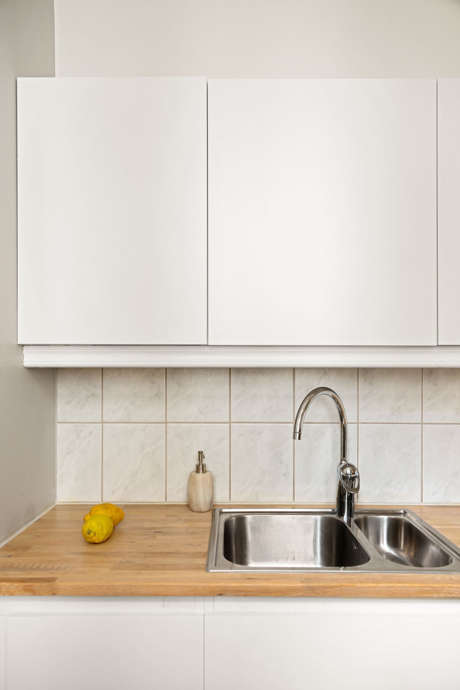 Dated kitchen with a wood countertop and old tile backsplash