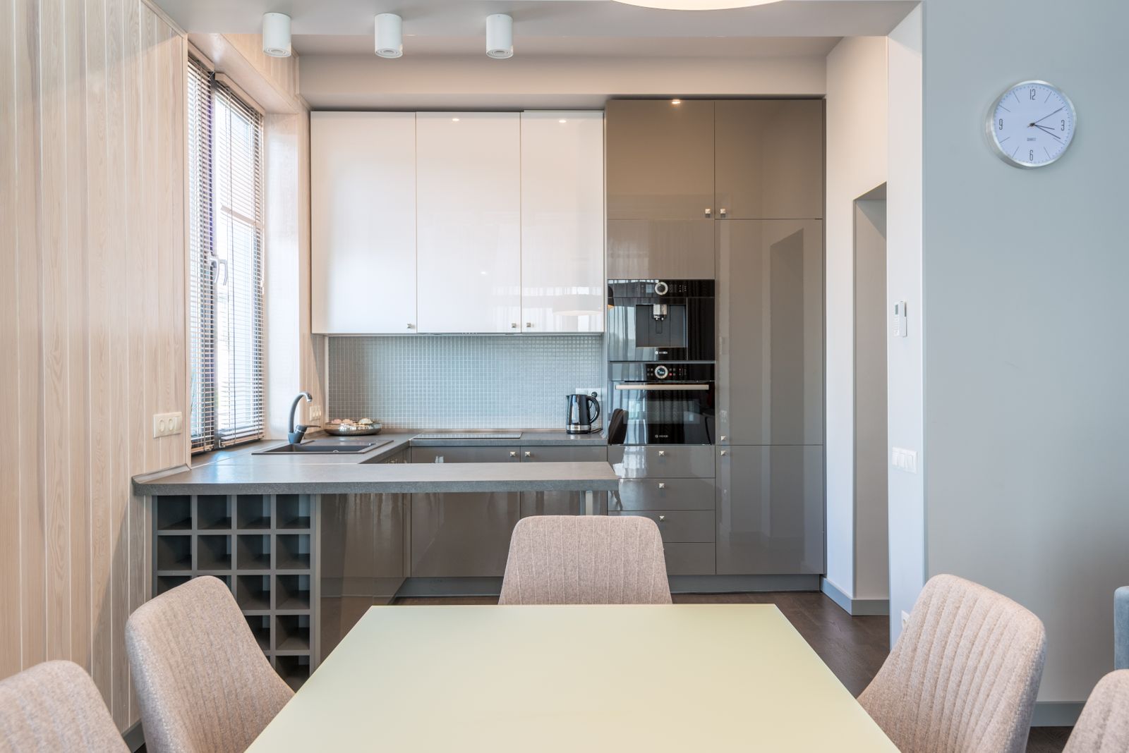 Finished kitchen opened to the dining room, with lacquered fronts and a stone countertop